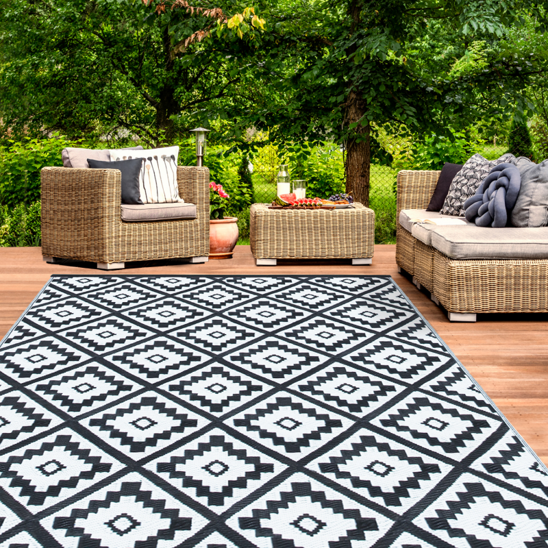 Salon avec canapé vert, coussins et tapis design noir & blanc et tabourets  noirs Stock Photo