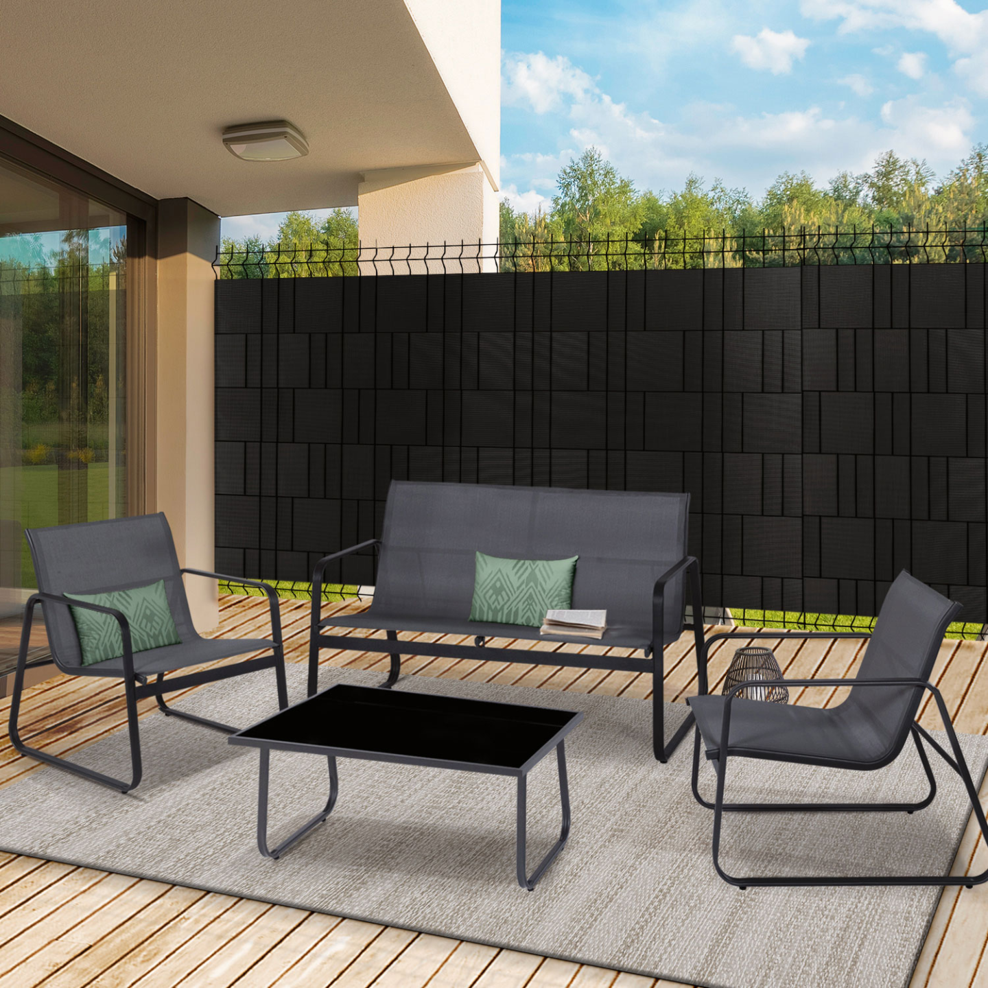 Brise-vue à lamelles souple noir fixé sur un grillage, installé derrière un salon de jardin pour préserver l’intimité de la terrasse