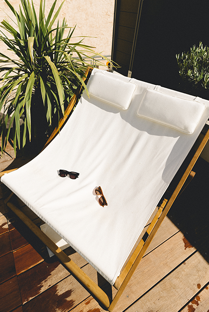 Lit de jardin double en bois et tissus couleur crème, sur une terrasse