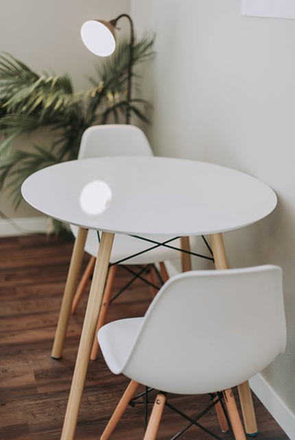 Une table blanche et ronde entourée de deux chaises scandinaves.