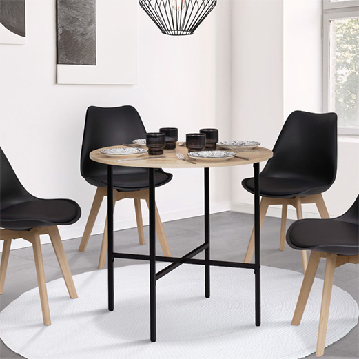 Quatre chaises noires au dossier incurvé autour d’une table ronde aux pieds en métal