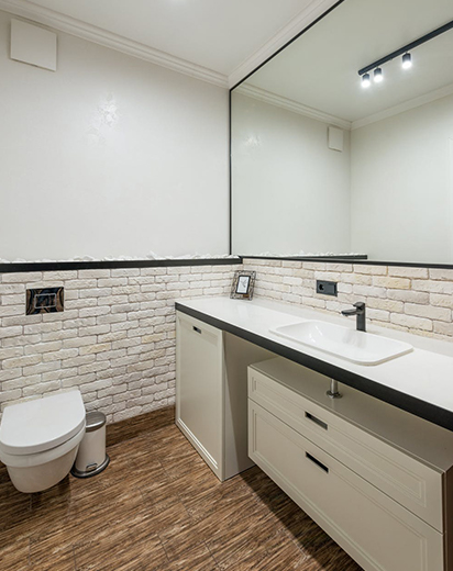 Toilettes dans salle de bain avec mur de brique