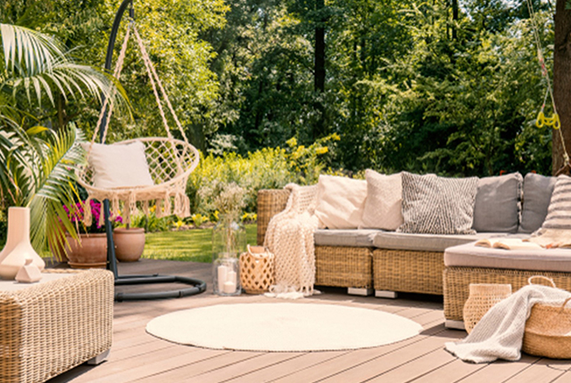 Un salon de jardin joliment décoré avec des coussin et des paniers