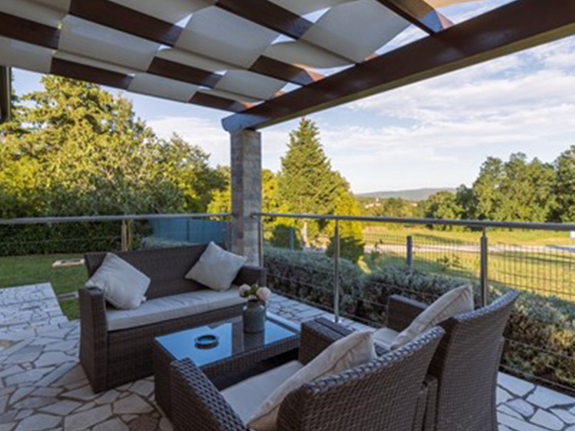 Salon de jardin en résine tressée sur une terrasse surplombant un jardin