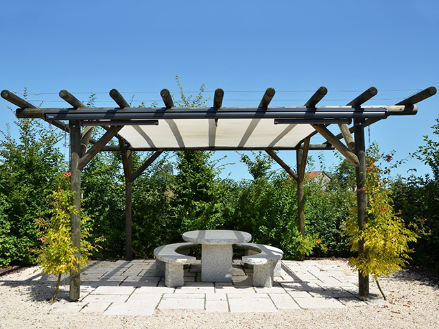 Une pergola surplombant une terrasse végétalisée