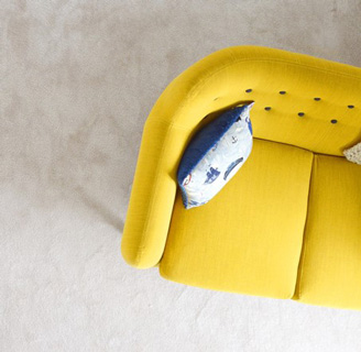 Un canapé scandinave jaune avec un coussin bleu