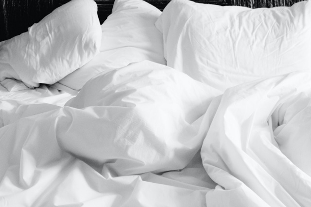 Une couette duveteuse et des oreillers moelleux sur un lit défait