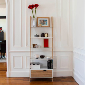 Dans un salon avec parquet, une étagère en bois blanc et hêtre est accolée au mur peint en blanc