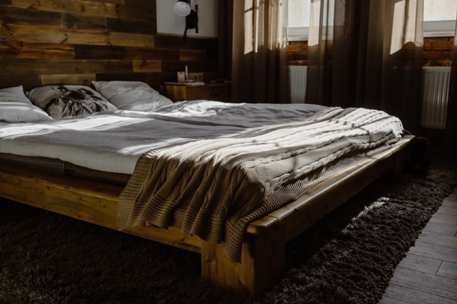 Un lit avec surmatelas dans une chambre à l’ambiance rustique