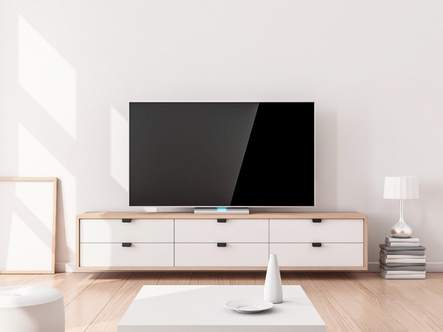 Télévision posée sur un meuble télé bas en bois comportant des tiroirs