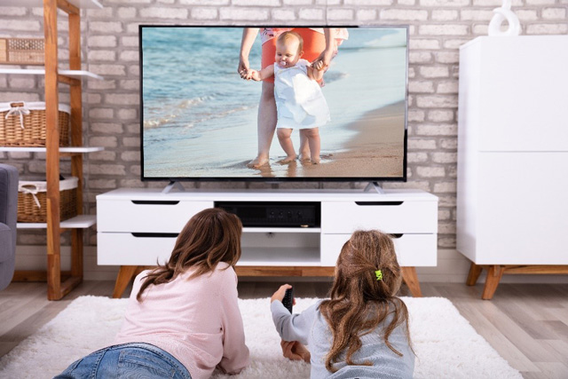 une mère et sa petite fille allongées devant la télévision