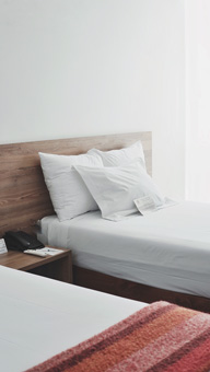 Deux oreillers sur un lit parfaitement fait, dans une chambre baignée de lumière