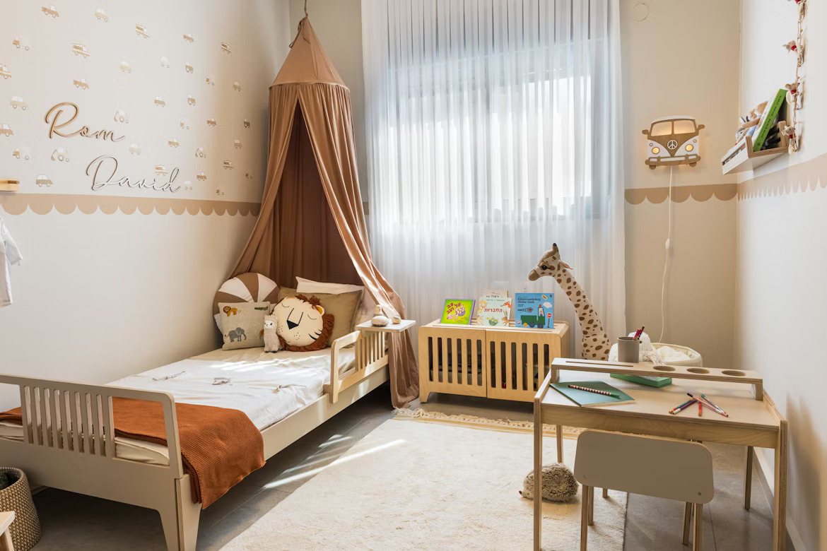 Chambre d’enfant avec lit à barrière, meuble de rangement et table pour les activités aux couleurs beige et caramel.