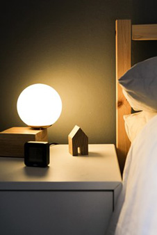 Une table de nuit épurée décorée d’un réveil et d’une lampe design
