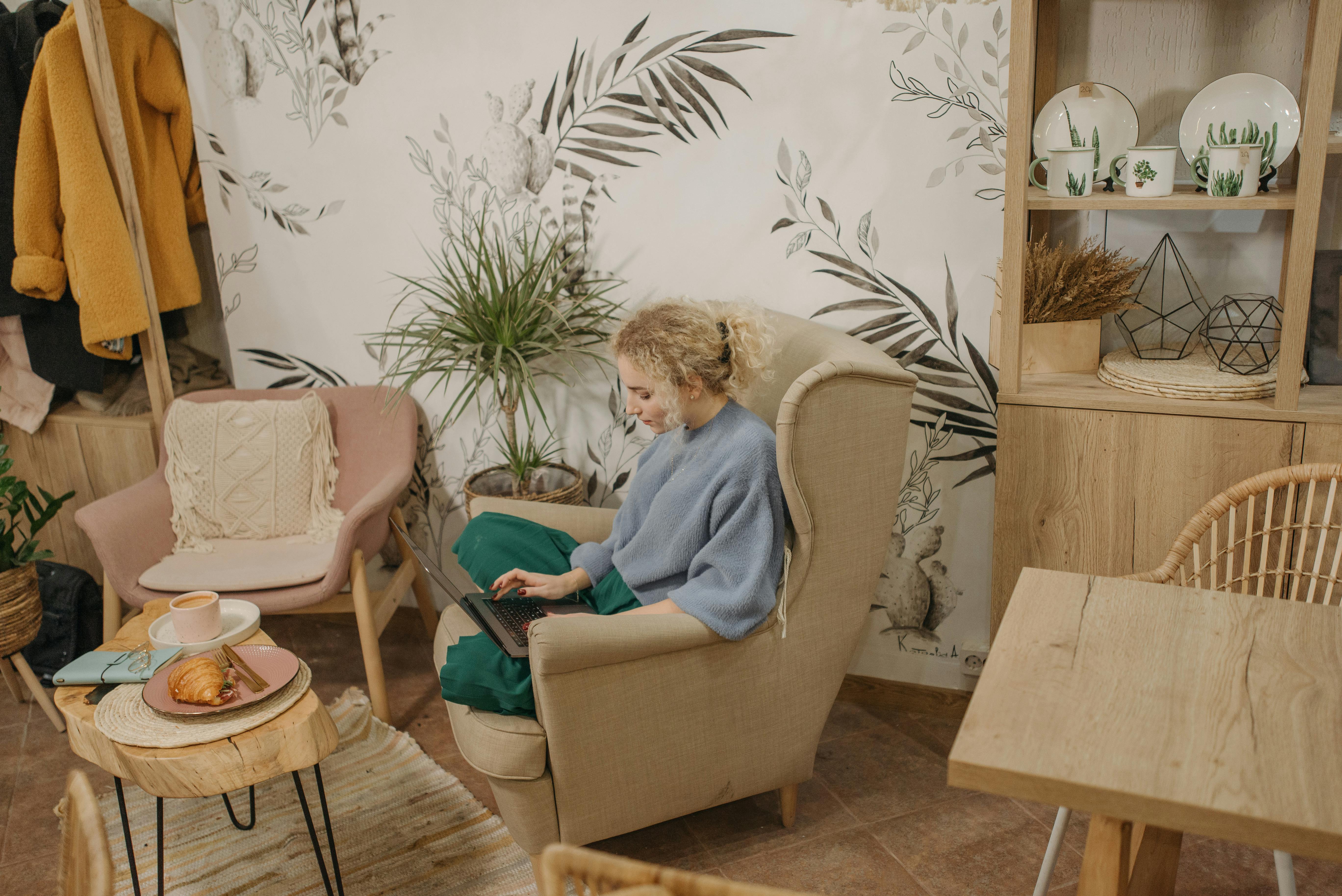 Salon avec fauteuil et textiles beiges, mobilier en bois et plantes pour une ambiance intérieure chaleureuse.
