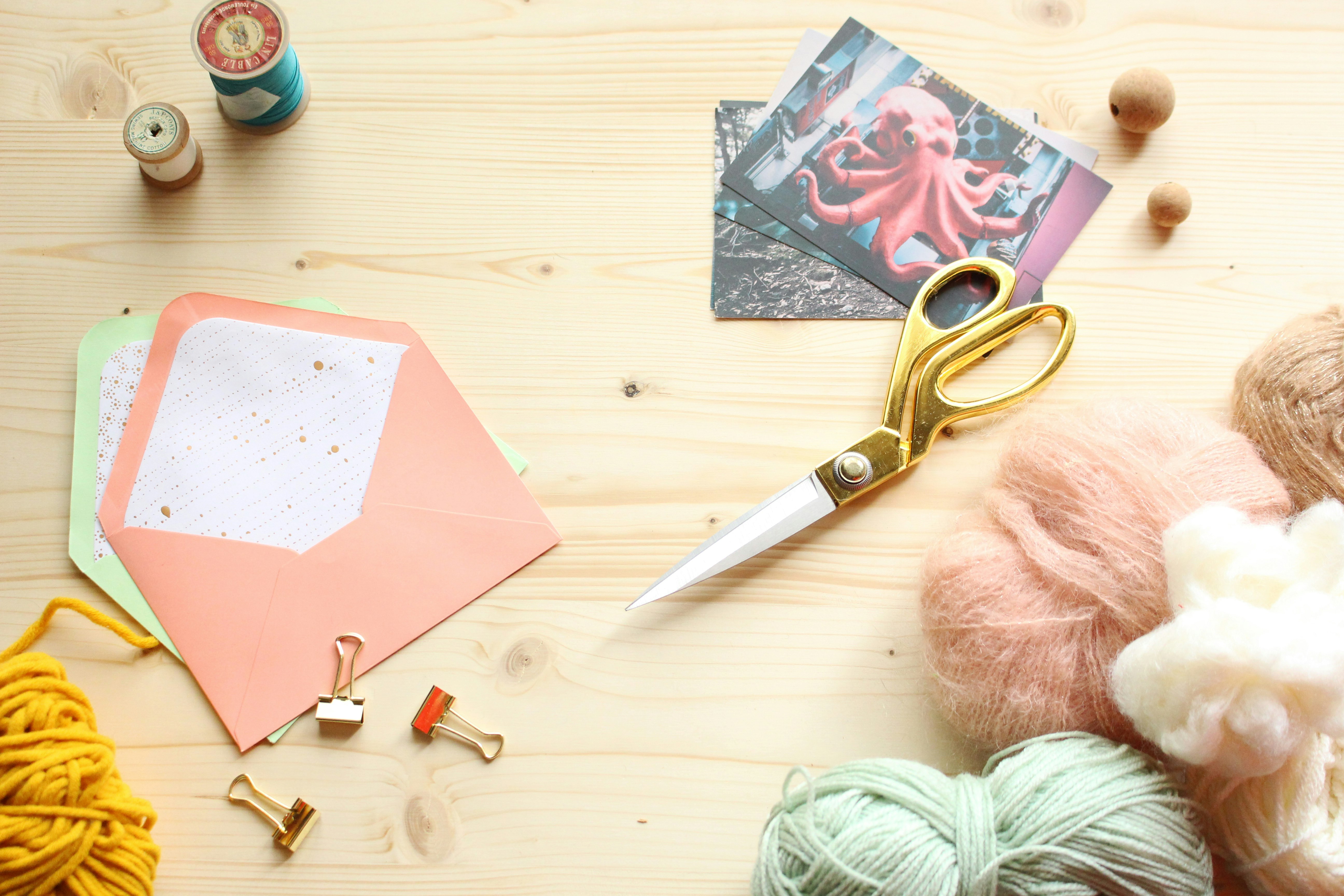 Matériel de loisirs créatifs sur table en bois avec ciseaux, fils, papier et accessoires DIY pour scrapbooking et activités créatives