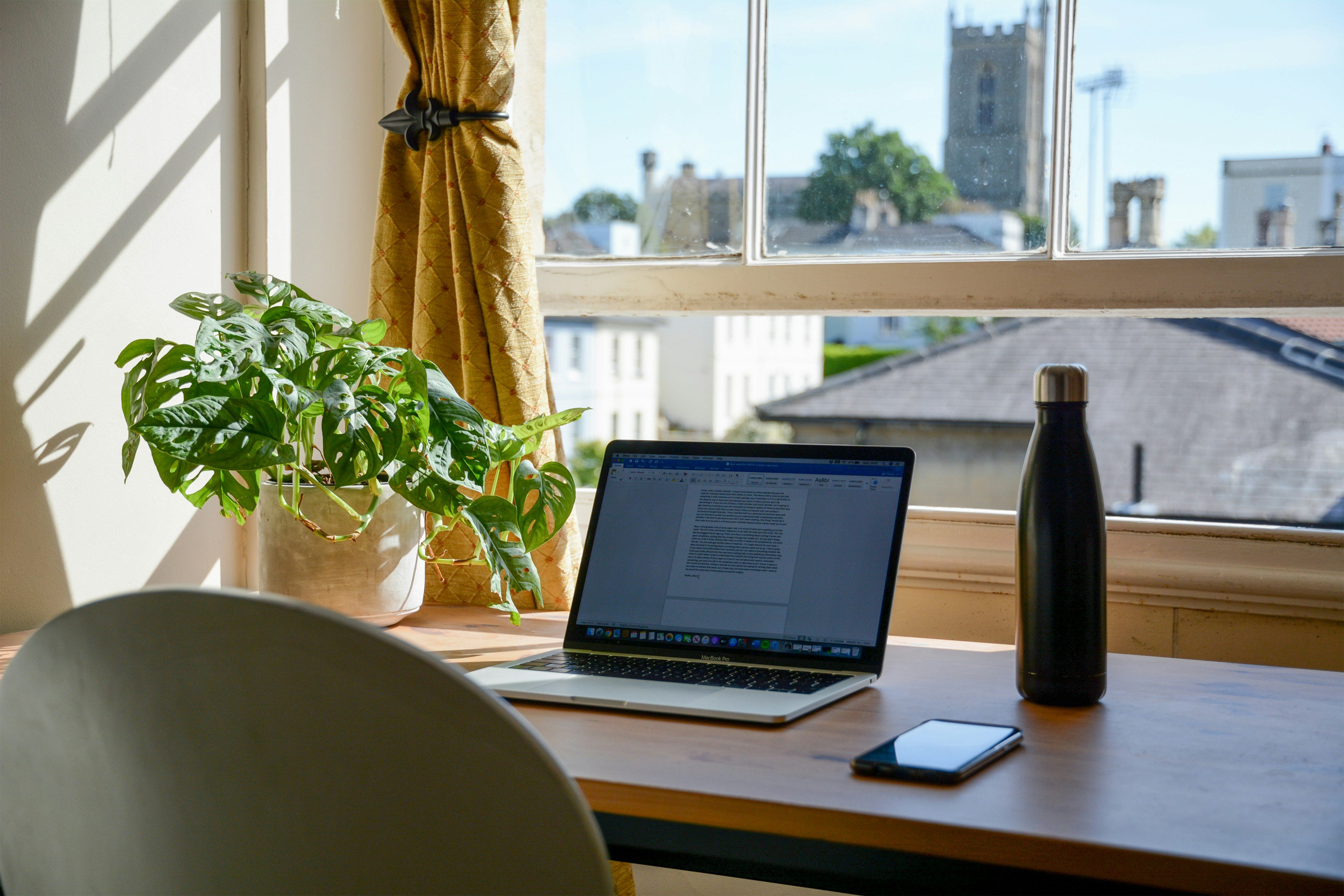 Coin bureau de travail lumineux au style scandinave et moderne avec chaise blanche, ordinateur portable et plantes vertes pour le télétravail