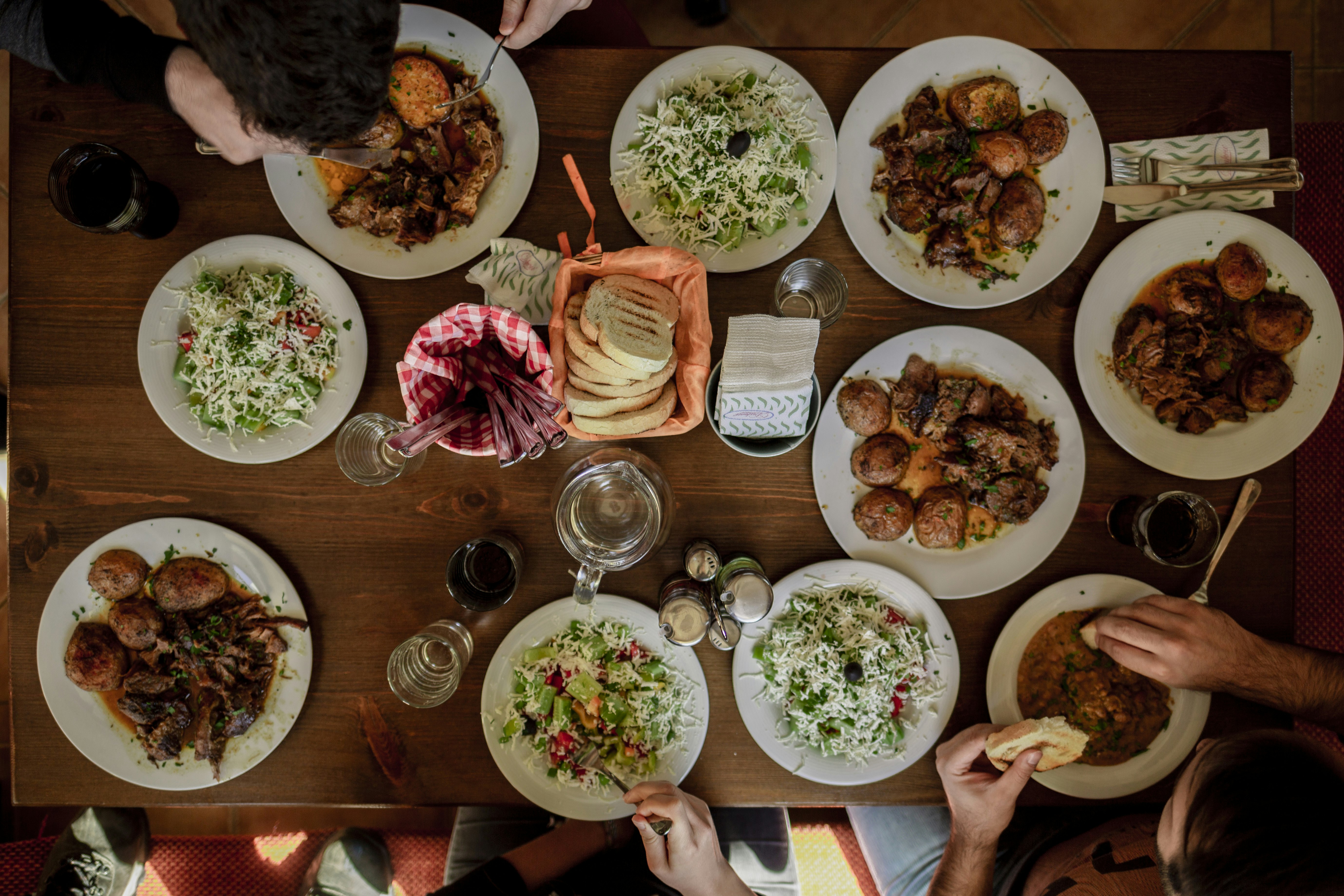 Grande tablée dressée pour un repas convivial avec des convives partageant plats et verres autour d'une table à manger.