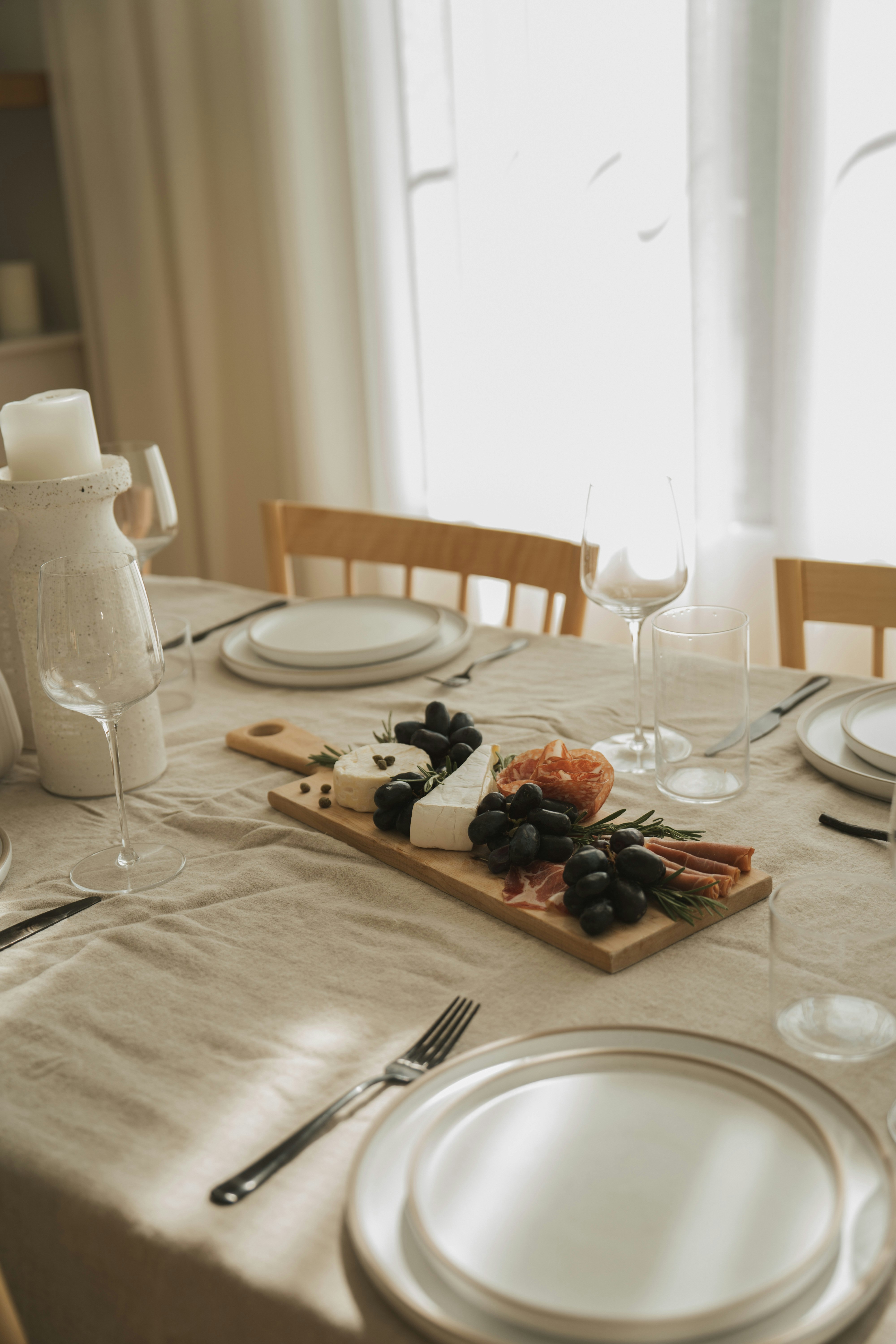 Une table dressée avec une nappe blanche sur laquelle sont posés des assiettes en céramique et des verres à pied